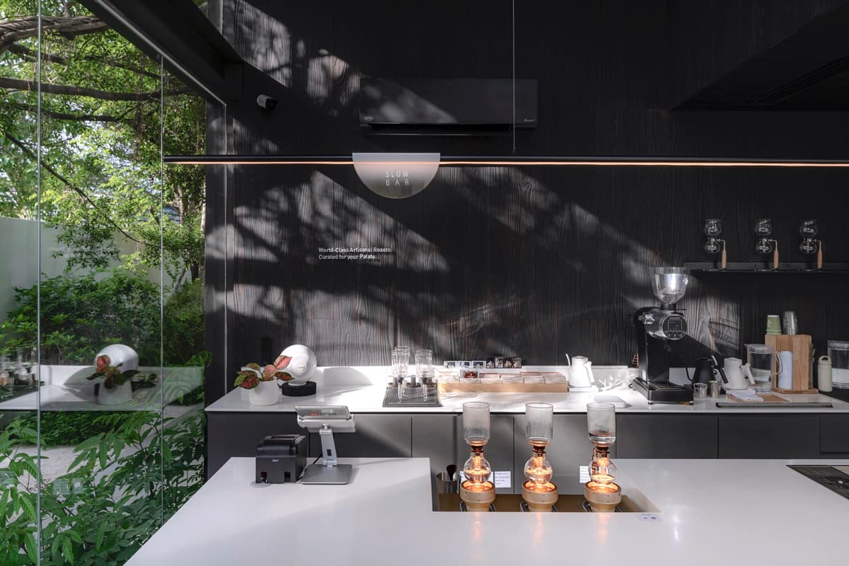 Кофейня «Nana Coffee Roasters», спроектированная бюроIDIN Architects, расположена в густонаселенном районе Бангна, Бангкок. Её основная цель — не ошеломить посетителя, а перенести его из городской суеты в спокойное и гармоничное пространство, где в центре внимания оказываются природа и сам кофе. Кофейня «Nana Coffee Roasters», спроектированная бюроIDIN Architects, расположена в густонаселенном районе Бангна, Бангкок. Её основная цель — не ошеломить посетителя, а перенести его из городской суеты в спокойное и гармоничное пространство, где в центре внимания оказываются природа и сам кофе.