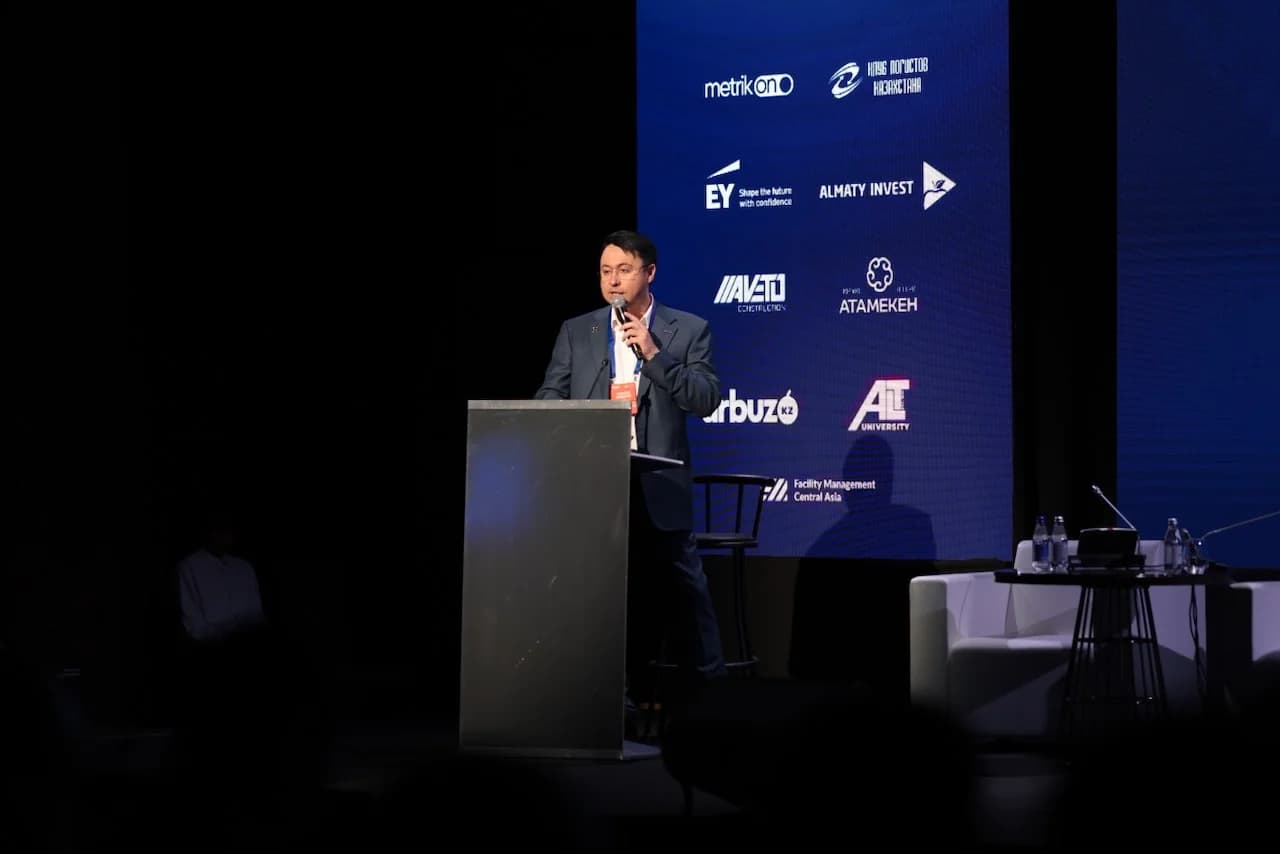 Станислав Ахмедзянов, управляющий партнер IBC Global, выступает с микрофоном за трибуной на фоне брендированного пресс-волла саммита CAWS 2026 Станислав Ахмедзянов, управляющий партнер IBC Global, выступает с микрофоном за трибуной на фоне брендированного пресс-волла саммита CAWS 2026