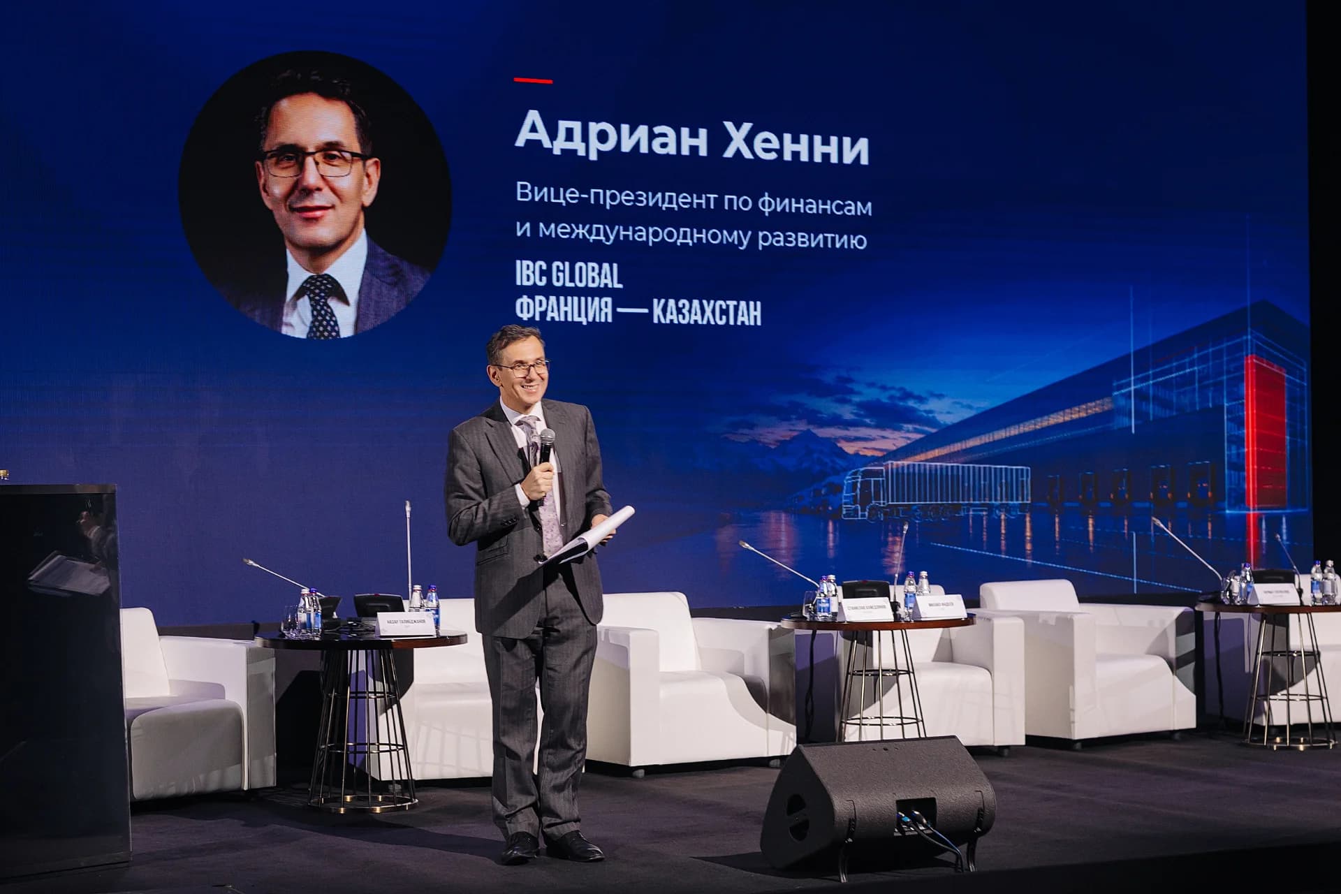 Вице-президент по финансам и международному развитию IBC Global Адриан Хенни выступает на сцене саммита CAWS 2026 с микрофоном в руках Вице-президент по финансам и международному развитию IBC Global Адриан Хенни выступает на сцене саммита CAWS 2026 с микрофоном в руках